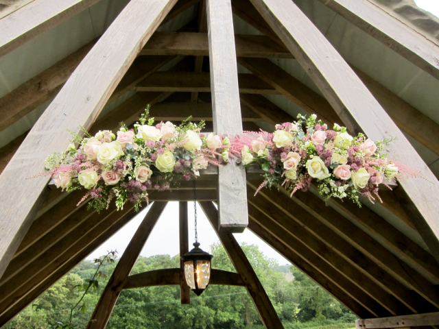 Two unique displays linking together decorating this stunning arbour. Floral design by Cotswold Blooms, wedding florist based in Cheltenham.