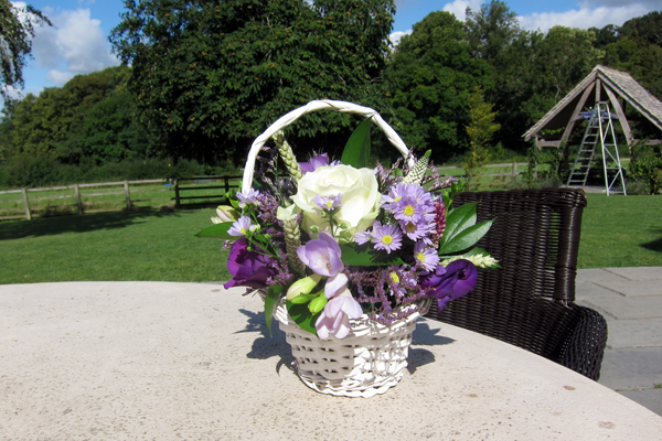 Flower girl basket display in purple, lilac and white at Hyde House, Stow-on-the-Wold. Floral design by Cotswold Blooms, wedding florist based in Cheltenham.