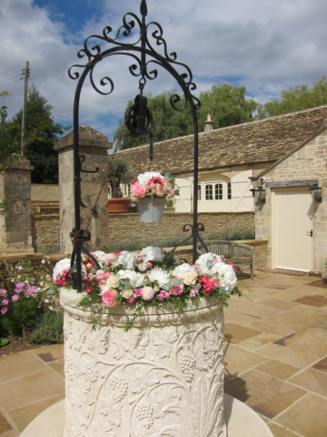 Well display for an outdoor wedding ceremony. Floral design by Cotswold Blooms, wedding florist based in Cheltenham.