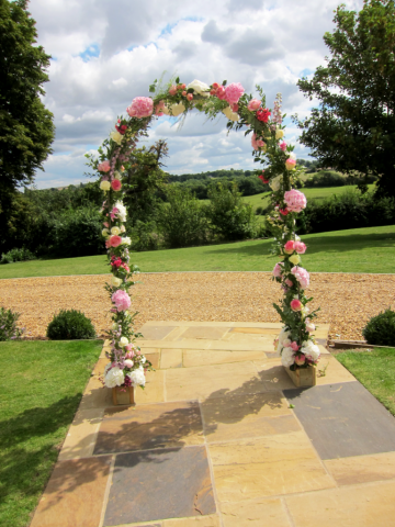 Freestanding arch display in pinks and white in a country garden style. Floral design by Cotswold Blooms, wedding florist based in Cheltenham.