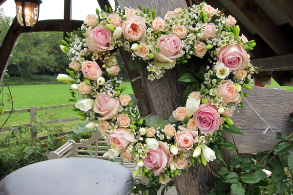 Heart display in pink and light peach for a romantic outdoor ceremony. Floral design by Cotswold Blooms, wedding florist based in Cheltenham.