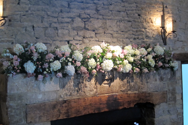 Mantel piece display in white and light pink at Cripps Barn. Floral design by Cotswold Blooms, wedding florist based in Cheltenham.