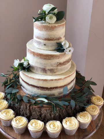 Mixed Eucalyptus with white Eustoma and Ranunculus dressing the wedding cake in small groups. Floral design by Cotswold Blooms, wedding florist based in Cheltenham.