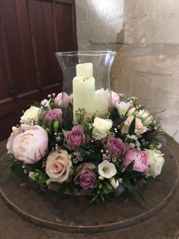 Hurricane vase mixed flower display around the base in Upper Slaughter Church. Floral design by Cotswold Blooms, wedding florist based in Cheltenham.