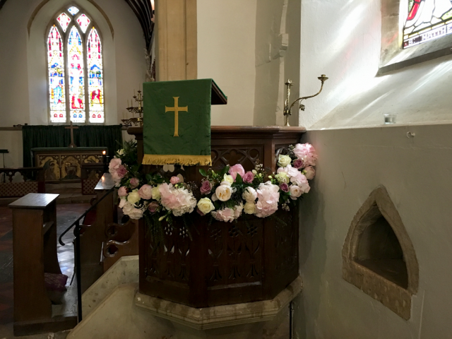 Light pink and white including Hydrangea, Roses and Waxflower around the church pulpit . Floral design by Cotswold Blooms, wedding florist based in Cheltenham.