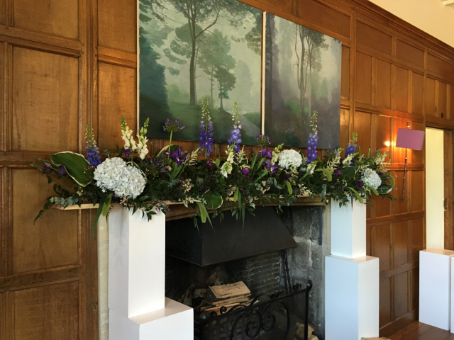 Natural growing display mantel piece display in purples and blue at Bibury Court. Floral design by Cotswold Blooms, wedding florist based in Cheltenham.