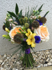 Natural hand tied bouquet in yellow, blue and peach including Stocks, Craspedia and Freesia. Floral design by Cotswold Blooms, wedding florist based in Cheltenham.
