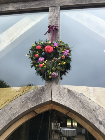 Coral, yellow and purple hanging heart at Cripps Barn. Floral design by Cotswold Blooms, wedding florist based in Cheltenham.