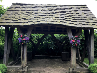 Coral, yellow and purple displays for an outdoor ceremony at Cripps Barn. Floral design by Cotswold Blooms, wedding florist based in Cheltenham.