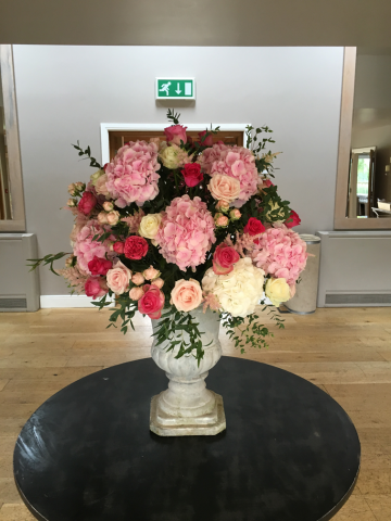 Mixed pink Roses, with Hydrangea in an all-round urn display. Floral design by Cotswold Blooms, wedding florist based in Cheltenham.