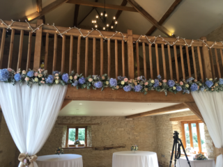 Light blue, peachy pinks and white across the balcony at Kingscote Manor. Floral design by Cotswold Blooms, wedding florist based in Cheltenham.