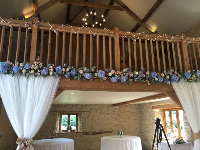 Light blue, peachy pinks and white across the balcony at Kingscote Manor. Floral design by Cotswold Blooms, wedding florist based in Cheltenham.