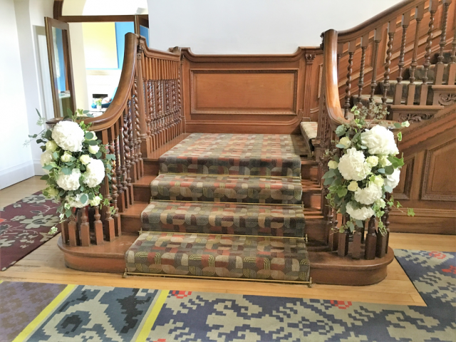 Stair case display in white with Eucalyptus, Hydrangea and Roses at Cowley Manor. Floral design by Cotswold Blooms, wedding florist based in Cheltenham.