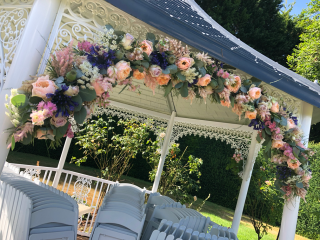 Peach, blue, light pink Roses, Agapanthus, Delphinium and Eucalyptus at Hockwold Hall. Floral design by Cotswold Blooms, wedding florist based in Cheltenham.