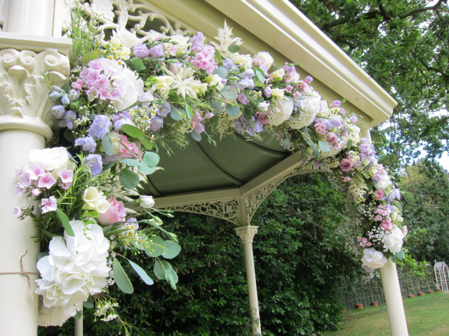 Wedding arch at Manor by the Lake, in lilac and creams in a country garden style. Floral design by Cotswold Blooms, wedding florist based in Cheltenham.