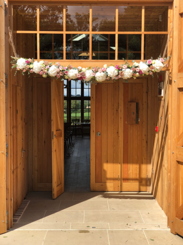 Mixed Roses and white Hydrangea display across the entrance to The Grange at Hyde House. Floral design by Cotswold Blooms, wedding florist based in Cheltenham.