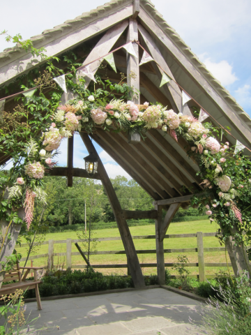 Light pink and white arch including Hydrangea, Astilbe, and Roses on the arbour at Hyde House. Floral design by Cotswold Blooms, wedding florist based in Cheltenham.