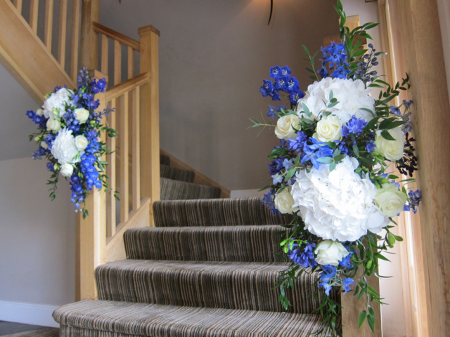 White and blue stair display including Delphinium, Hydrangea, Roses and foliage. Floral design by Cotswold Blooms, wedding florist based in Cheltenham.