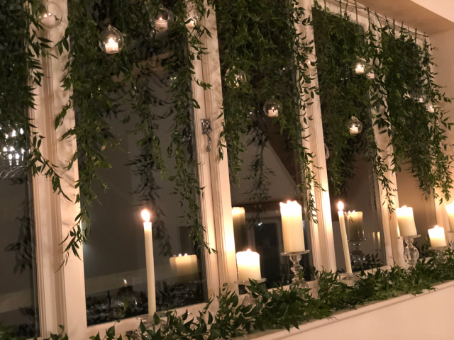 Window display of Ruscus with candles and hanging tea lights at Hyde House. Floral design by Cotswold Blooms, wedding florist based in Cheltenham.