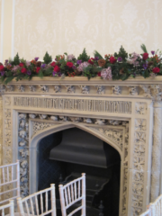 Winter wedding mantel piece display in raspberry and purple at Eastington Park. Floral design by Cotswold Blooms, wedding florist based in Cheltenham.