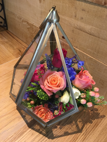 Coral, pink and blue with Delphinium, Roses, and Freesia in a terrarium. Floral design by Cotswold Blooms, wedding florist based in Cheltenham.