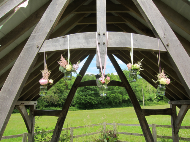 Hanging jars decorating the arbour at Hyde House. Floral design by Cotswold Blooms, wedding florist based in Cheltenham.