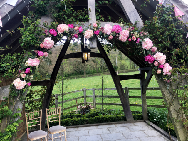 Bright and light pink arch display for an outdoor wedding. Floral design by Cotswold Blooms, wedding florist based in Cheltenham.