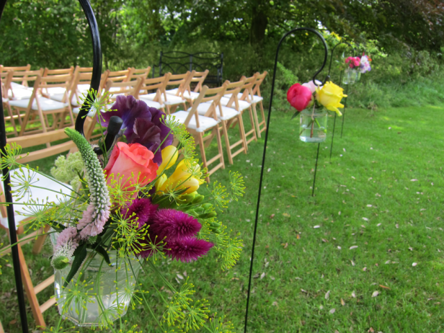 Bright and vibrant jars hanging on Sheppard’s hooks for an outdoor wedding at Barnsley House. Floral design by Cotswold Blooms, wedding florist based in Cheltenham.