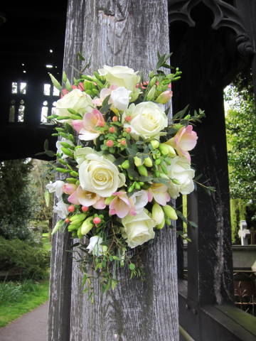 Roses, Freesia, Hypericum and foliage at the entrance to St Marys Church, Charlton Kings. Floral design by Cotswold Blooms, wedding florist based in Cheltenham.