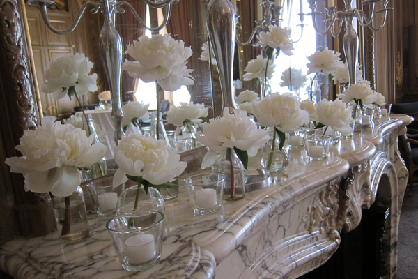Peonies in specimen vases with tea light on the mantel piece at Claridges, London. Floral design by Cotswold Blooms, wedding florist based in Cheltenham.
