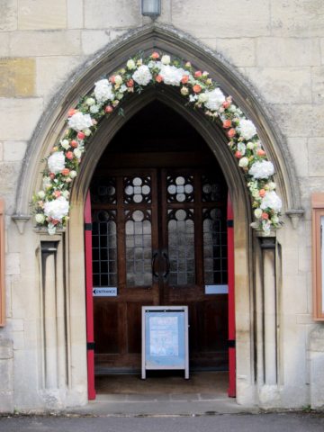 Coral and white Roses, Hydrangea, Hypericum and Freesia at St Mary’s Church, Charlton Kings. Floral design by Cotswold Blooms, wedding florist based in Cheltenham.