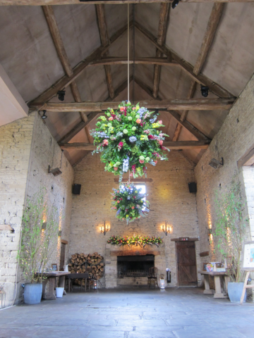 Bright and bold flower balls in coral, lime green, yellow and raspberry at Cripps Barn. Floral design by Cotswold Blooms, wedding florist based in Cheltenham.