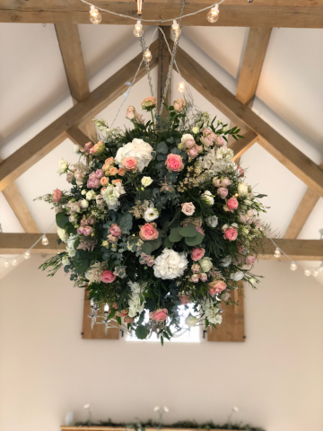 Flower ball of Roses, Delphinium, Hydrangea, Waxflower and mixed foliage, hanging at Hyde House. Floral design by Cotswold Blooms, wedding florist based in Cheltenham.