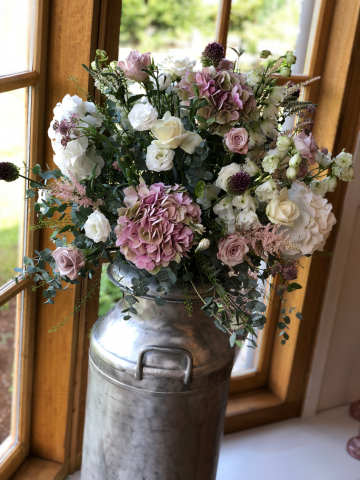 Milk churn with vintage pinks, and whites including allium, Hydrangea, Roses, and Astilbe. Floral design by Cotswold Blooms, wedding florist based in Cheltenham.