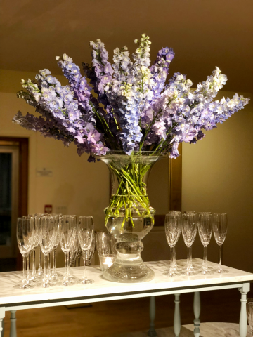 Blue Delphinium in light blue in a glass urn. Floral design by Cotswold Blooms, wedding florist based in Cheltenham.