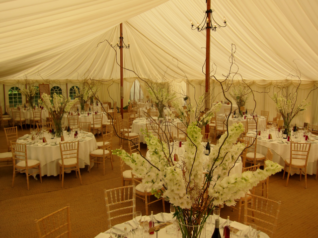 Delphinium and willow table centre tables at a marquee wedding. Floral design by Cotswold Blooms, wedding florist based in Cheltenham.