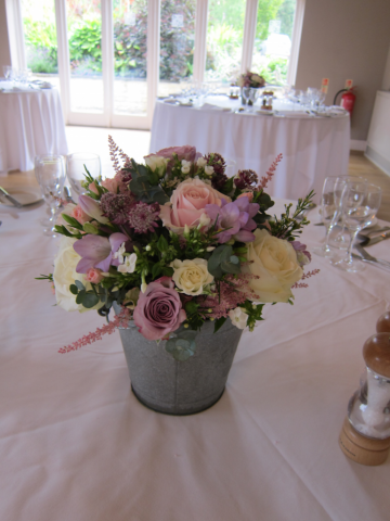 Rustic tins with cream and pink floral display table centres at Hyde House, Stow-on-the-Wold. Floral design by Cotswold Blooms, wedding florist based in Cheltenham.