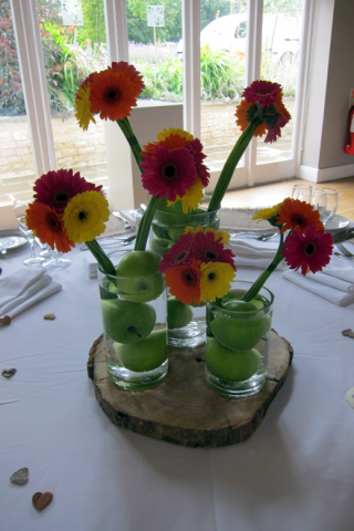 Gerbera and apple table centre wedding displays at Hyde House. Floral design by Cotswold Blooms, wedding florist based in Cheltenham.