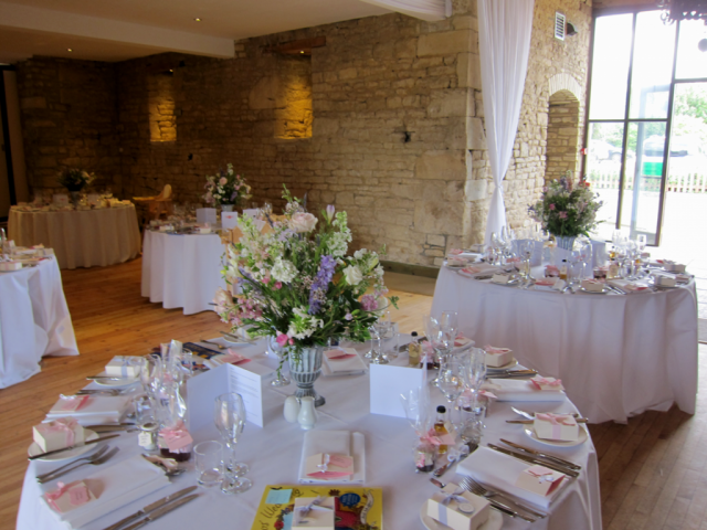 Miniture urns with country garden displays in pastel shades at The Great Tythe Barn, Tetbury. Floral design by Cotswold Blooms, wedding florist based in Cheltenham.