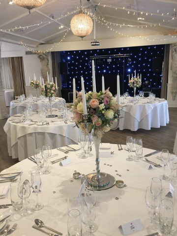 Silver candelabras with stunning flower balls on a mirror base. Floral design by Cotswold Blooms, wedding florist based in Cheltenham.