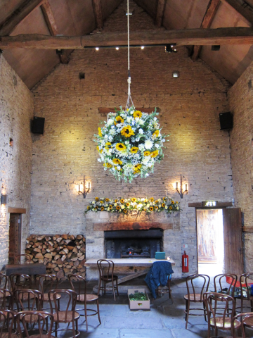 Stunning flower ball and mantel piece display designed with Sunflowers, Chrysanthemums, Gypsophila and Eustoma at Cripps Barn.  Floral design by Cotswold Blooms, wedding florist based in Cheltenham.