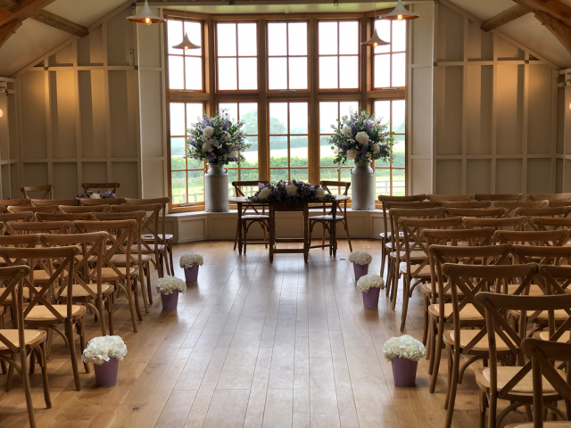 Milk churns and a long and low display with Hydrangea isle markers at the Grange, Hyde House. Floral design by Cotswold Blooms, wedding florist based in Cheltenham.