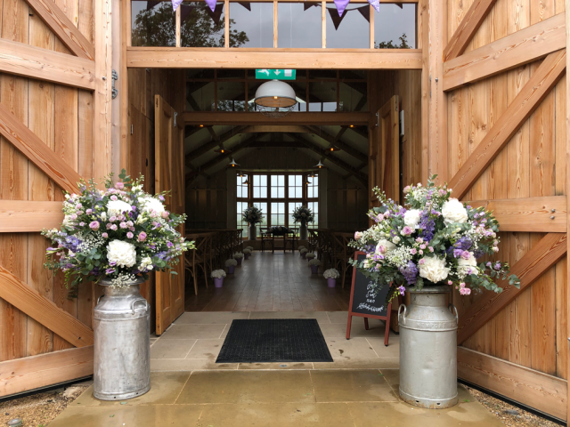 Milk churns and a long and low display with Hydrangea isle markers at the Grange, Hyde House. Floral design by Cotswold Blooms, wedding florist based in Cheltenham.