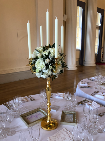 Gold candelabra with a white flower ball, for a winter wedding at Pittville Pump Rooms, Cheltenham. Floral design by Cotswold Blooms, wedding florist based in Cheltenham.