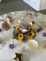 Sunflower and Freesia table centre on a round mirror base at The Manor House Hotel, Moreton-in-Marsh. Floral design by Cotswold Blooms, wedding florist based in Cheltenham.