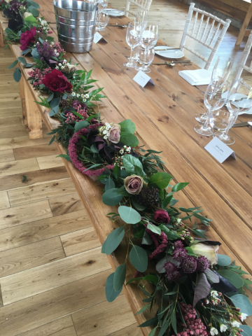 A mixed foliage table runner with Pepperberry and Roses at Elmore Court. Floral design by Cotswold Blooms, wedding florist based in Cheltenham.