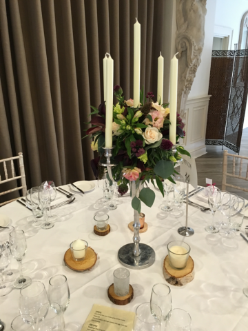 A candelabra with natural display in burgundy and blush pinks at Manor by the Lake, Cheltenham. Floral design by Cotswold Blooms, wedding florist based in Cheltenham.