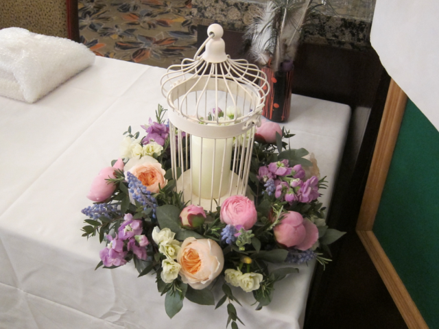 A pastle colour theme, with flowers and foliage surrounding a bird cage at the Rembrandt Hotel, London. Floral design by Cotswold Blooms, wedding florist based in Cheltenham.