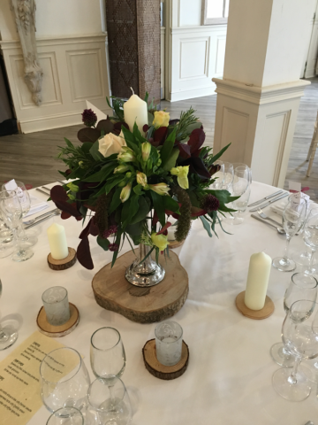A natural table centre display in burgundy and blush pinks at Manor by the Lake, Cheltenham. Floral design by Cotswold Blooms, wedding florist based in Cheltenham.