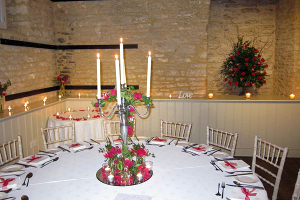 Beautiful wedding breakfast with large numbers of candles creating a magical evening. Floral design by Cotswold Blooms, wedding florist based in Cheltenham.